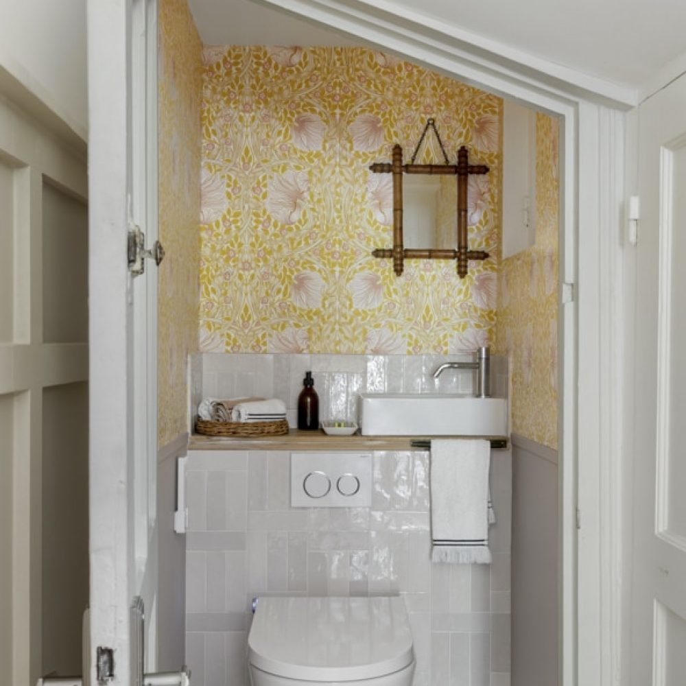 Toilettes élégantes et singulières avec zelliges roses, papier peint William Morris et miroir rétro, pour une ambiance raffinée et chaleureuse dans une maison de charme au Touquet.